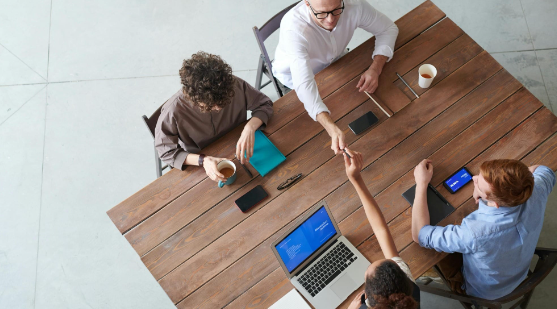 Image showing colleagues sitting at a table together in an office, used in an employee feedback form template.